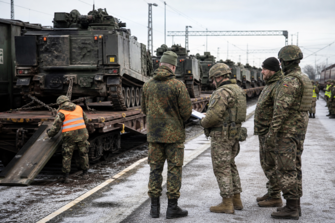NATO-Truppen koordinieren die Entladung gepanzerter Fahrzeuge an einem deutschen Bahnterminal [Bildinhalt mit KI erstellt]